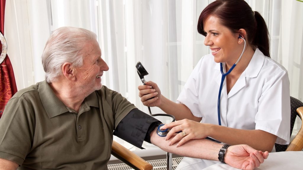 A young woman doctor measures the blood pressure of dementia patient who refuses help/support
