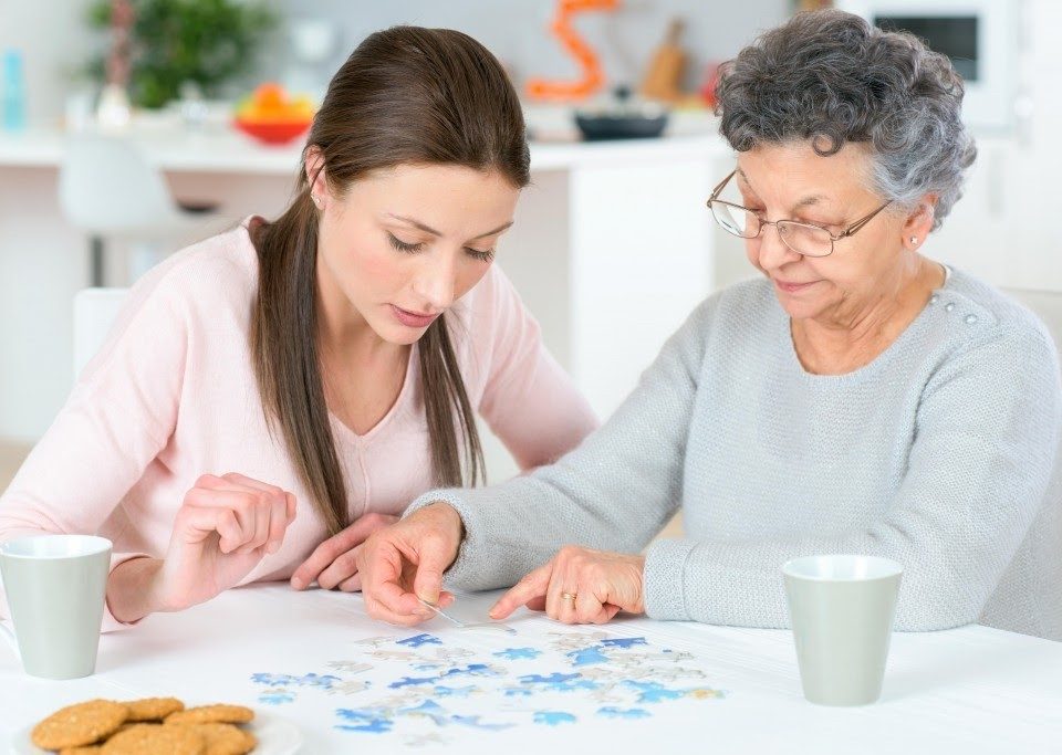 female senior engaging with female caregiver, doing a puzzle