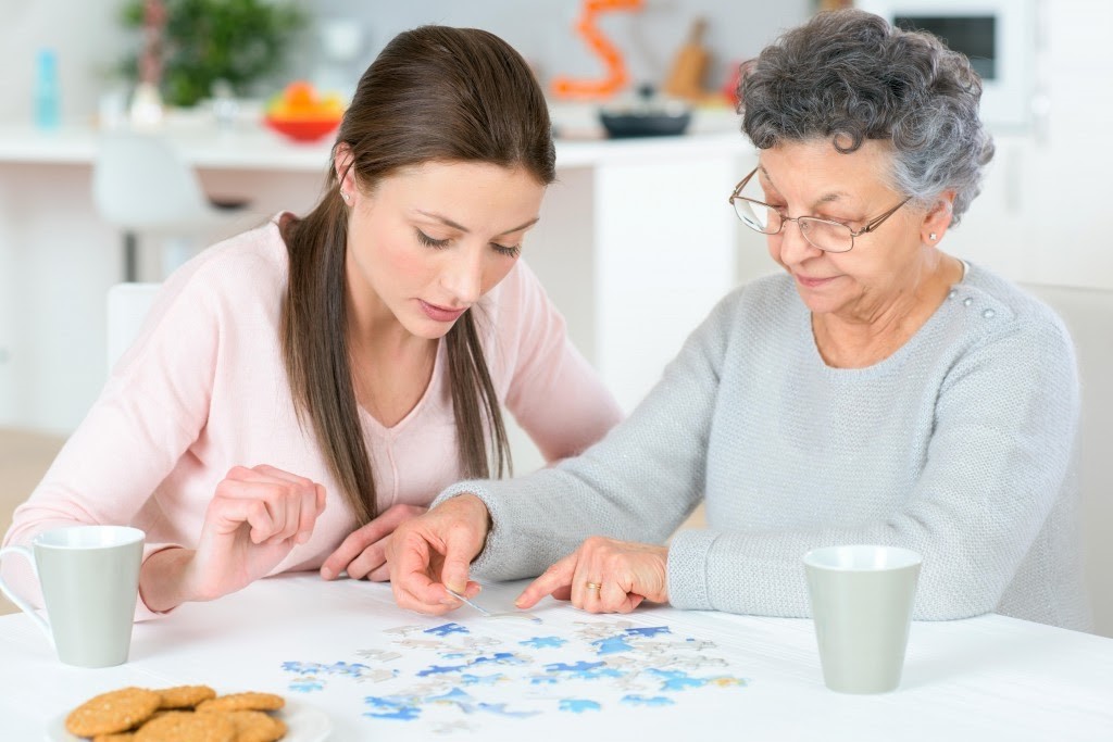 female senior engaging with female caregiver, doing a puzzle