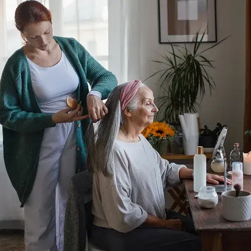 Caregiver helping her client with a hairstyle.